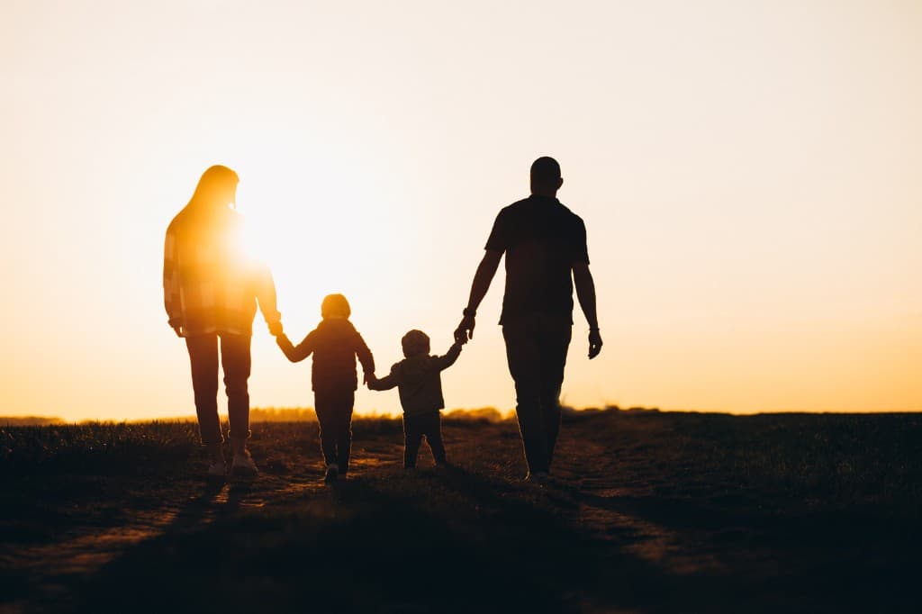 Una familia camina de la mano al atardecer.